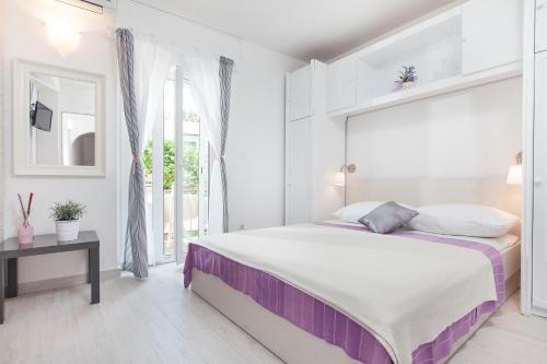 a white bedroom with a large bed and a window at Apartments Orka in Promajna