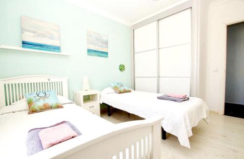 2 camas en una habitación blanca con ventanas en 2 bedrooms villa with sea view private pool and furnished terrace at Benalmadena 2 km away from the beach, en Benalmádena