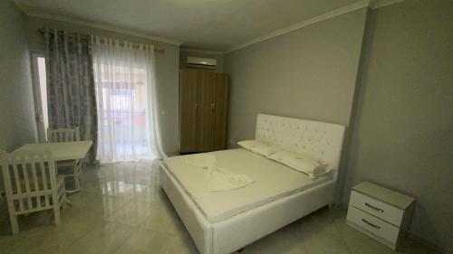ein kleines Schlafzimmer mit einem weißen Bett und einem Tisch in der Unterkunft Ami's Apartment in Sarandë