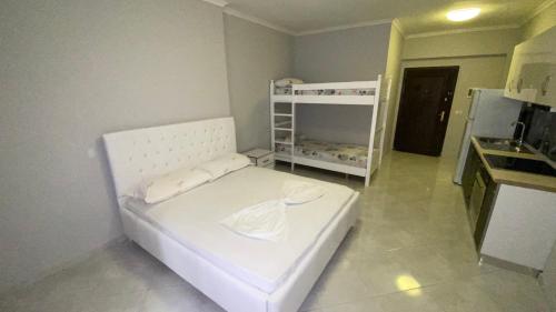 ein weißes Bett in einem Zimmer mit Küche in der Unterkunft Ami's Apartment in Sarandë