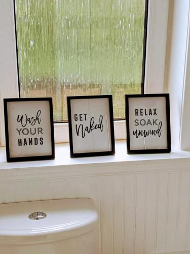 three framed pictures on a window sill above a toilet at Glenclova - No 5 Bellyeoman, bright two bedroom apartment in Fife