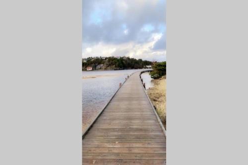 a wooden boardwalk stretches out into the water at Nybygd feriebolig rett ved strand til leie! in Kristiansand