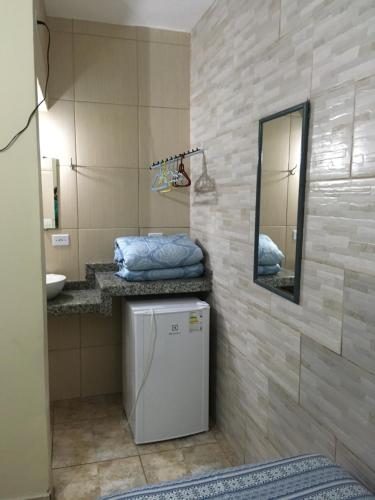 a bathroom with a small refrigerator and a mirror at Residencial Beira Mar Cananéia in Cananéia