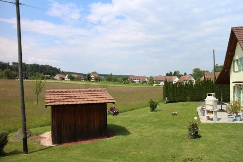 a smallshed in a yard next to a house at Les Petites Chambres de la Bleue Maison in Coeuve