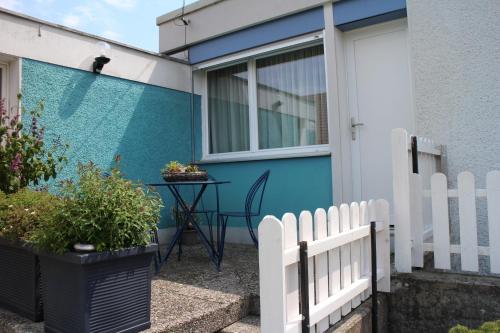a white picket fence in front of a house at Les Petites Chambres de la Bleue Maison in Coeuve
