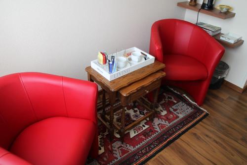 two red chairs sitting in a room with a table at Les Petites Chambres de la Bleue Maison in Coeuve