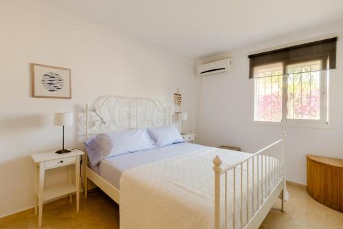 Un dormitorio blanco con una cama blanca y una ventana en Apartamento Confortable Urbanización El Paraiso en Estepona