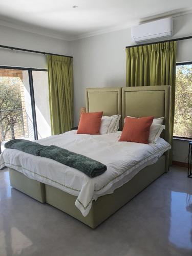 1 dormitorio con 1 cama grande con almohadas rojas en Via Lactea en Mmafefe