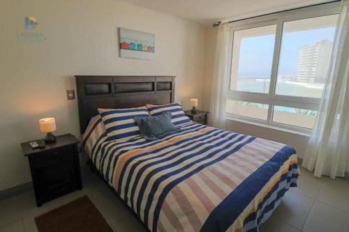 um quarto com uma cama com um cobertor listrado e uma janela em Departamento La Serena Laguna del Mar em La Serena