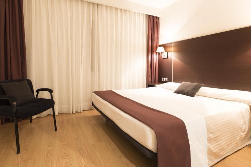 a hotel room with a large bed and a chair at Hotel Plazaola in Irurtzun
