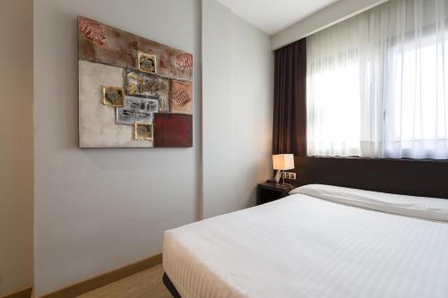 伊魯爾孫的住宿－普拉薩奧拉酒店，卧室配有一张床,墙上挂有绘画作品