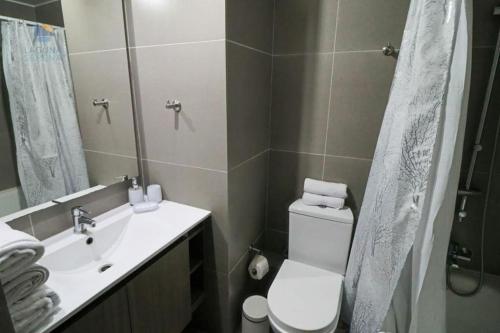 a bathroom with a toilet and a sink and a mirror at Departamento La Serena Laguna del Mar in La Serena