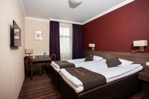 a hotel room with two beds and a desk at Hotel Cēsis in Cēsis