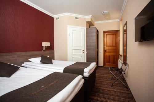 a hotel room with two beds and a television at Hotel Cēsis in Cēsis