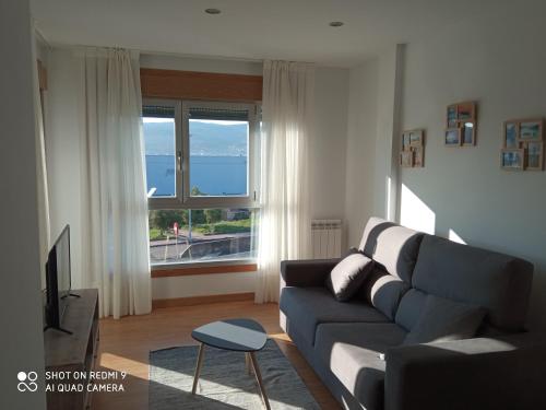 uma sala de estar com um sofá e uma grande janela em El pisito de Lourizan em Pontevedra
