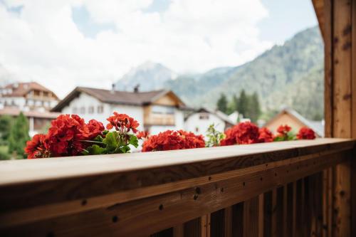 a bunch of red flowers on a wooden balcony at Alpine Chalet Sauter in San Vigilio Di Marebbe