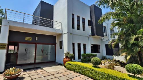 a white building with glass doors and palm trees at Khayalami Hotel - Mbombela in Nelspruit