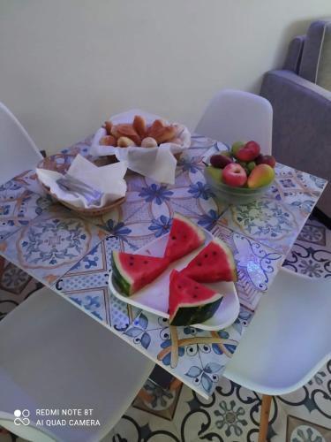 a table with a plate of watermelon and fruit on it at Casa vacanze Maison Zio Bruno A' Scalinatella in Naples