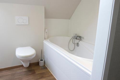 La salle de bains blanche est pourvue de toilettes et d'une baignoire. dans l'établissement Cosy & charming holiday house in Damme, à Damme
