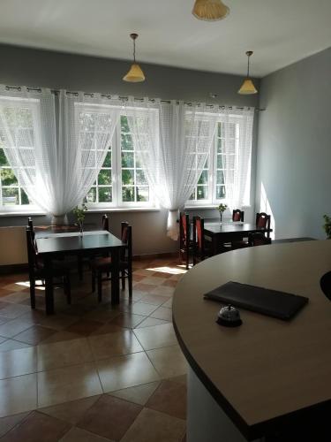 a dining room with tables and chairs and windows at Hotel Fregata in Pęczniew