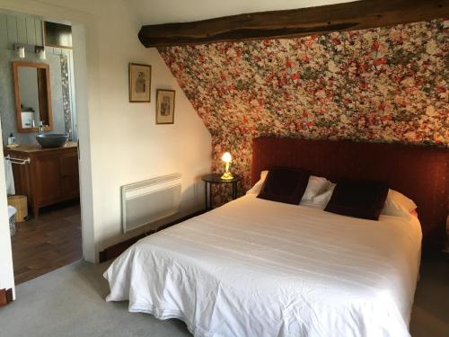 ein Schlafzimmer mit einem großen Bett mit Blumenwand in der Unterkunft Le Moulin de l`Epinay in Sainte-Beuve-en-Rivière