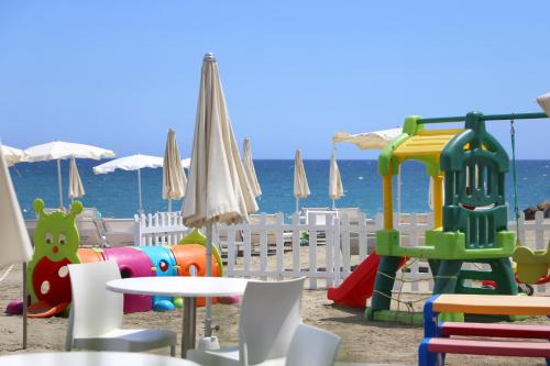 un parque infantil en la playa con mesa y sillas en Hotel Caravelle Thalasso & Wellness, en Diano Marina