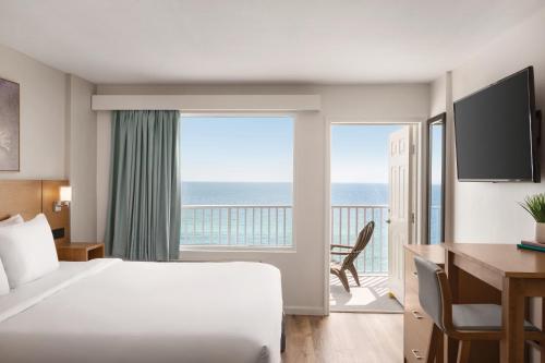 a hotel room with a bed and a balcony with the ocean at Radisson Beachfront Hotel - Panama City Beach in Panama City Beach