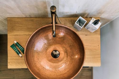 a copper sink on a wooden counter with cosmetics at Relais Cocci Grifoni - Panoramic Wine Resort in Offida