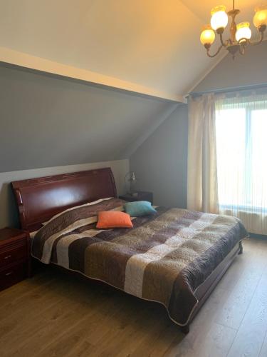 a bedroom with a large bed with an orange pillow on it at Pūteļkrogs in Tērvete