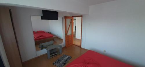 Habitación pequeña con cama roja y espejo. en Gabriel Apartment Sos Constantei Etaj 4 en Mangalia