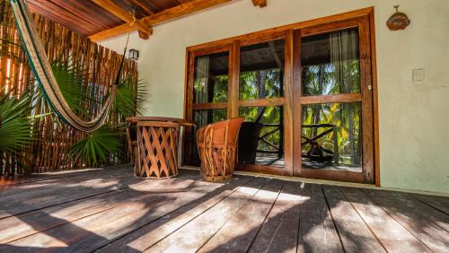 a porch with a large glass door and two chairs at Zomay Beachfront Holbox in Holbox Island