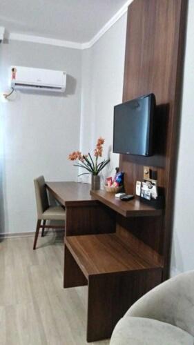 a living room with a desk with a tv on it at Class Hotel Varginha in Varginha