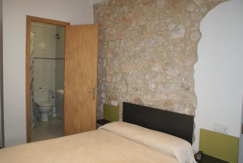 1 dormitorio con cama y pared de piedra en Pensió i Apartament Torrent, en L'Escala