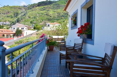 a balcony of a house with chairs and flowers at Teixeira House in Arco da Calheta