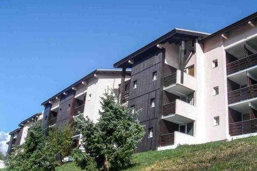 an apartment building with a tree in front of it at Petit appartement Labellisé Les 2 Alpes résidence Arc en Ciel télésiège Petite Aiguille in Les Deux Alpes