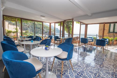 un restaurante con sillas azules, mesas y ventanas en Palazzo Vingius, en Minori