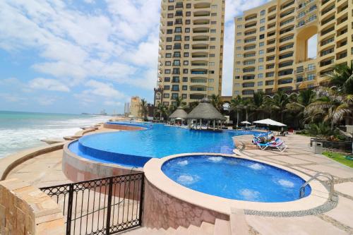 a large swimming pool next to the ocean with buildings at Departamento en Gavias Grand Mazatlan 920 Torre Sur in Mazatlán