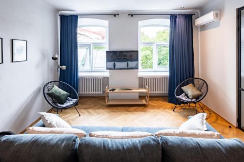 a living room with a blue couch and two chairs at OnLviv Apartments Rynok Square 18/2 in Lviv