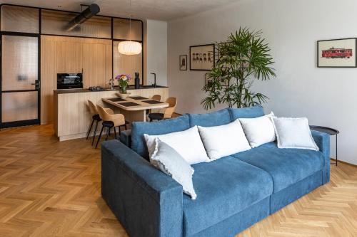 a living room with a blue couch and a kitchen at OnLviv Apartments Rynok Square 18/2 in Lviv