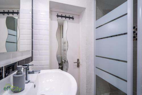 une salle de bain blanche avec un lavabo et un miroir dans l'établissement Cœur de Bordeaux, à Bordeaux