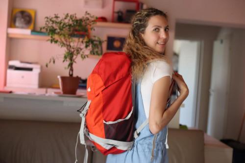 a girl is holding a backpack in a room at Ostello La Salana in Capannori