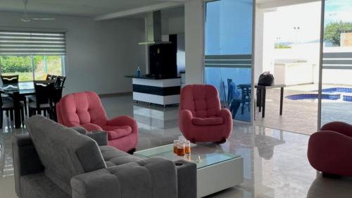 een woonkamer met rode stoelen en een tafel bij Casa Vacacional con Piscina Privada en Girardot in Girardot