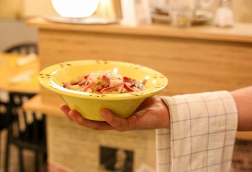 a person holding a yellow bowl of food at Ostello La Salana in Capannori