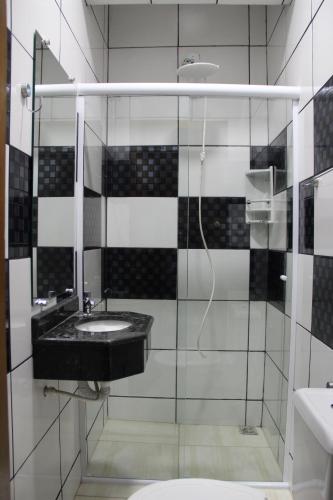 a black and white bathroom with a sink and a shower at Hotel Joia Fina in Aparecida
