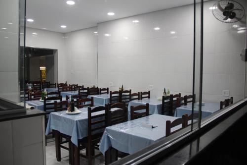 a dining room with tables and chairs and a mirror at Hotel Joia Fina in Aparecida