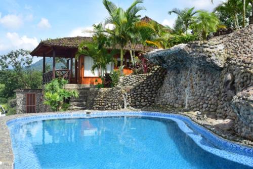 eine Villa mit einem Pool vor einem Haus in der Unterkunft Pie in the Sky 1 Gorgeous Cottage with spectacular scenic views in El Fosforo