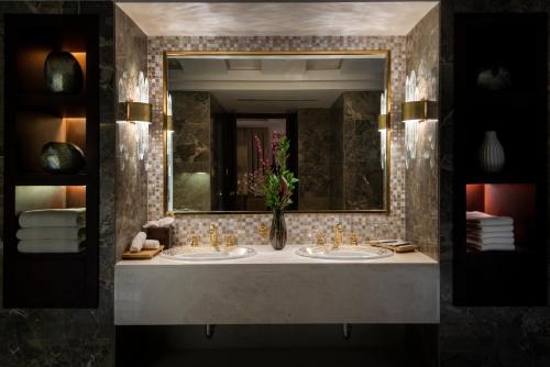a bathroom with two sinks with a vase of flowers at Vittori Palace Hotel and Residences in Riyadh