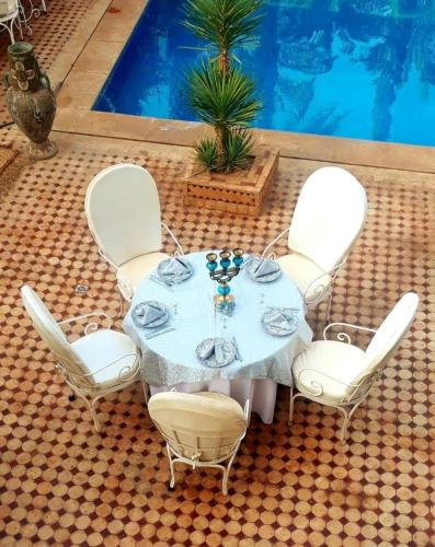 a table with white chairs and a pool at Riad Dar Sofian in Zagora
