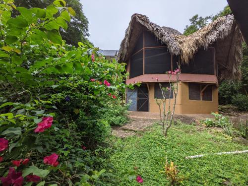 a house with a thatched roof and flowers at Finca del Sol Eco Lodge in Santa Cruz