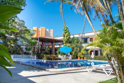 une piscine avec des palmiers en face d'un hôtel dans l'établissement Hotel Hacienda Vallarta - Playa Las Glorias, à Puerto Vallarta